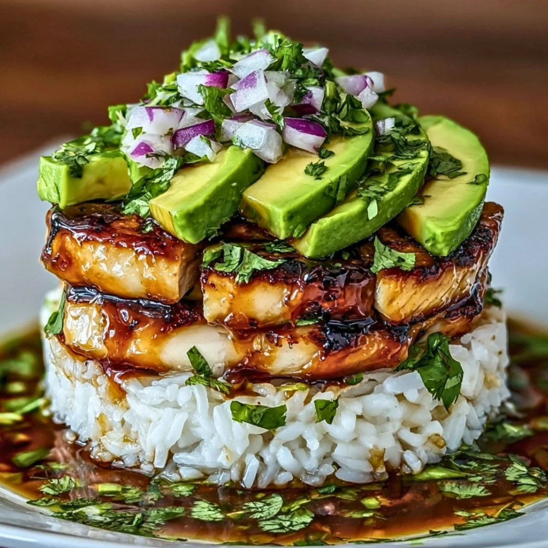 Plate of Honey Lime Chicken with Avocado Rice Stack garnished with fresh herbs.