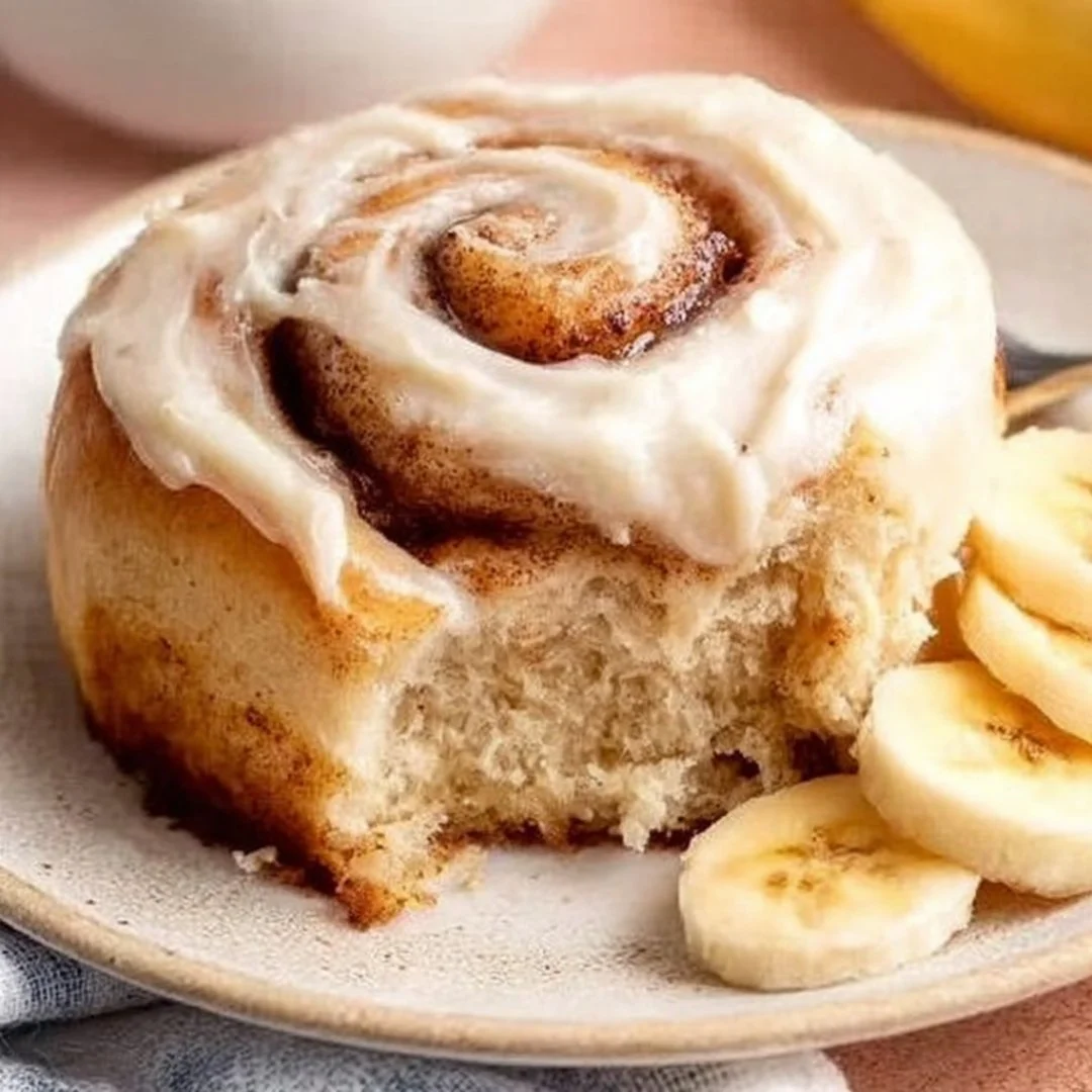 Delicious banana bread cinnamon rolls with cream cheese frosting on a plate