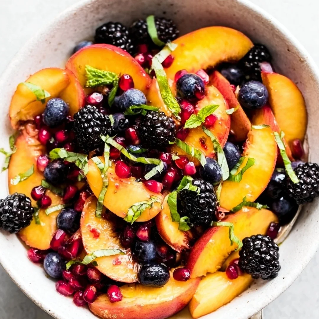 Honey Lime Basil Peach Fruit Salad served in a bowl with fresh peaches and basil